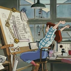 a person sitting at a desk with a drawing on the easel in front of them