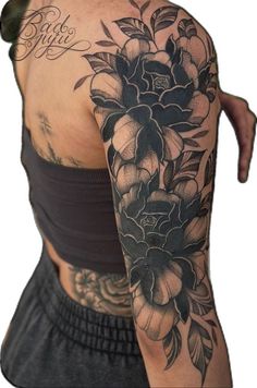 the back of a woman's arm with tattoos on it and flowers in black ink