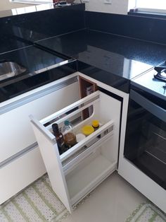 an open refrigerator door in a kitchen with black counter tops and white cabinets on both sides