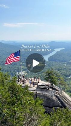 an american flag flying on top of a mountain overlooking the valley and river in north carolina