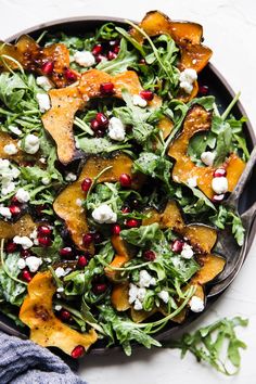 a salad with spinach, feta cheese and pomegranate on top