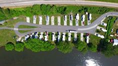 an aerial view of rv park next to a river and road with cars parked on it