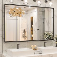 a bathroom with two sinks and a large mirror over the sink that has lights on it