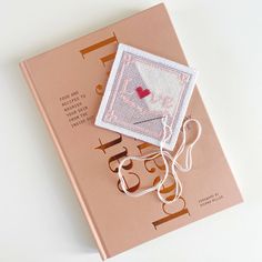 a cross stitch book with scissors and thread on it, sitting on a white surface