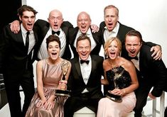 a group of men and women posing for a photo with an award in their hands