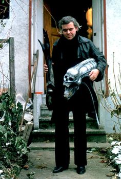 a man holding a pair of skis standing in front of a door with a skull mask on it