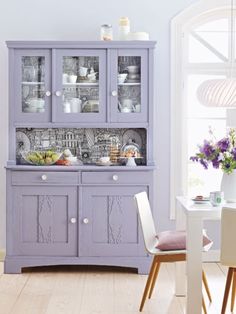 a purple china cabinet with glass doors in a dining room