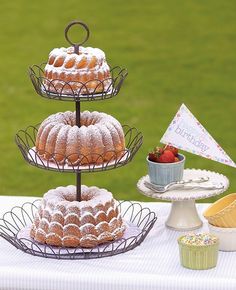 three tiered trays with cakes and cupcakes on them sitting on a table