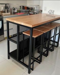 a kitchen island with three stools and a wooden counter top in the middle of it