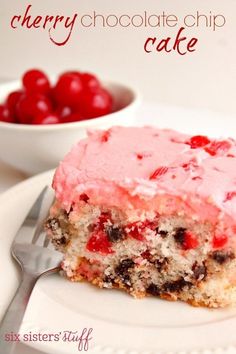 a piece of cherry chocolate chip cake on a plate with a fork and bowl of cherries in the background