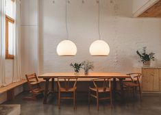 a dining room table with two lamps hanging from the ceiling