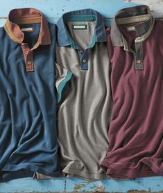 three men's polo shirts lined up against a blue wall