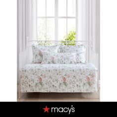 a white daybed with pink flowers on it in front of a window