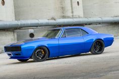 a blue muscle car parked in front of a building