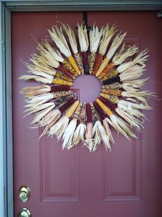 a wreath made out of dried corn sits on the front door's red door