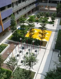 an aerial view of a courtyard with trees and bushes in the foreground, surrounded by buildings