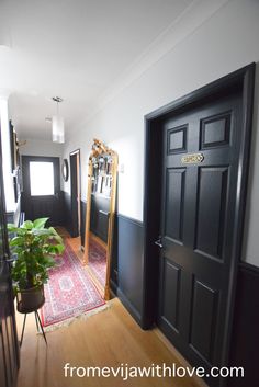 a hallway with black doors and a rug on the floor next to an open door