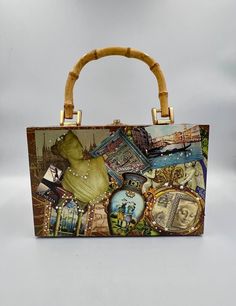 This is a fun, unique bag! The box style is decoupaged with colorful and unique images of art, angels, France, Italy and more. The front side has small rhinestones scattered about. Each side from top to bottom is covered in a different image, all beautiful. It has a bamboo handle and a brass flip closure and hinges. Opens like a jewelry box. The inside is lined in gold satin and has a mirror attached to the top. The mirror is scratched, but it doesn't show on the outside. It measures approximately 5.25 (with handle 9) x 8.25 x 3.75 inches. In great vintage condition. This would make a great gift!  Please keep in mind that I offer vintage and pre-owned items that may show normal signs of use including fading, small stains, scratches, chips or dings. See all photos and descriptions before pu Elegant Hand Painted Rectangular Bag, Vintage Box Bag With Detachable Top Handle, Luxury Hand Painted Rectangular Bags, Vintage Hand Painted Rectangular Bag, Vintage Decoupage, Vintage Formal Box Bag With Gold-tone Hardware, France Italy, Unique Images, Decoupage Box