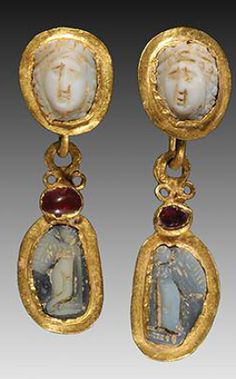 PAIR OF OPENWORK ROMAN GOLD EAR PENDANTS WITH CAMEOS of a facing female on the upper section of each and suspending a gold pendant with cameos of Eros figures; adorned with garnets. Ca. 3rd Century AD. Imperiul Roman, Ancient Roman Jewelry, Ancient Beads, Ancient Jewels, Gold Inspiration, Roman Jewelry, Ancient Jewellery, Geek Jewelry, Historical Jewellery