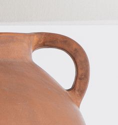 a large brown vase sitting on top of a white table next to a light colored wall