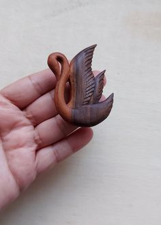 a small wooden bird sitting on top of a persons hand