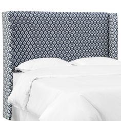 an upholstered headboard with white linens and blue patterns on the fabric