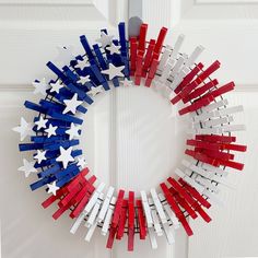 a wreath made out of red, white and blue wooden sticks is hanging on the front door