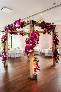 a wooden cross decorated with purple flowers on top of a hard wood floored room