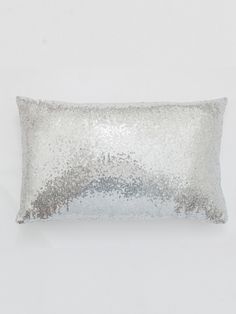 a silver sequin pillow sitting on top of a white wall