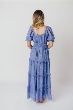 This gorgeous dress reminds us of a bluebonnet field in spring - its feminine silhouette and stunning hue is a welcome reminder that warm weather is just around the corner! The Kimmy Maxi Dress offers a multi-tiered skirt and flattering, gathered bodice with puffed sleeves. It's simple to dress up but comfortable enough for more casual wear; it's a stunning choice for any fashionista! FIT: Runs true to size. MATERIAL: GARMENT DETAILS: Lightweight maxi dress in a textured floral print, with a gat Spring Floral Print Maxi Prairie Dress, Spring Ditsy Floral Print Maxi Dress For Brunch, Spring Maxi Dress With Ditsy Floral Print For Brunch, Tiered Ditsy Floral Print Dress For Spring, Spring Prairie Dress With Ruffles For Garden Party, Flowy Prairie Dress For Garden Party In Spring, Spring Tiered Dress With Ditsy Floral Print, Short Sleeve Prairie Dress For Spring Garden Party, Blue Midi Dress For Spring Garden Party