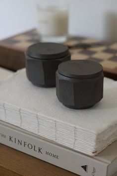 two black candles sitting on top of a stack of books next to a glass of milk