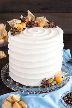 a white frosted cake sitting on top of a glass plate next to other dessert items