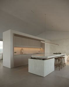 the kitchen is very large and has an island with stools in front of it