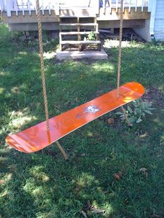 an orange skateboard sitting on top of a wooden swing in the middle of a yard