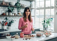 a woman standing in front of a kitchen counter with food on the counter and bowls