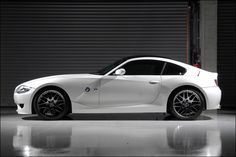 a white sports car parked in front of a garage door