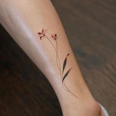 a small flower tattoo on the left ankle and right leg, with leaves coming out of it