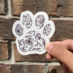 a hand holding up a sticker that says love with flowers and butterflies on it