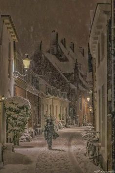 a person walking down a snowy street at night