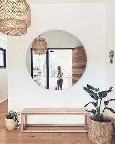 a mirror that is on the wall above a bench and potted plant in front of it