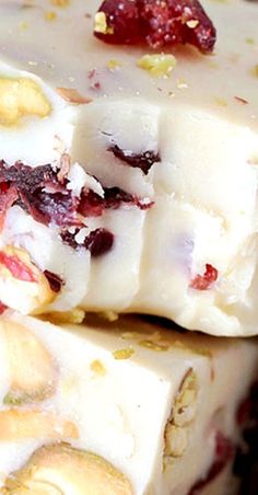 two pieces of white chocolate with cranberries and nuts on top, sitting next to each other