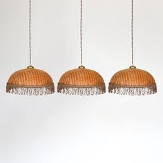 three hanging lamps with tassels on them against a white background, one is brown and the other is beige