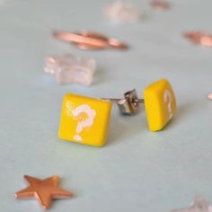 two yellow cufflinks with question marks on them, surrounded by tiny gold stars