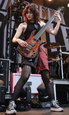 a woman in fishnet stockings and tights playing an electric guitar at a concert