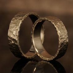 two gold wedding rings sitting next to each other on top of a black tablecloth