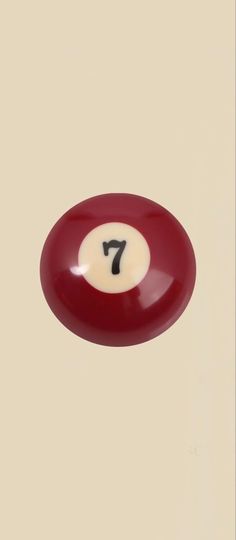 a red and white pool ball with the number seven in it's center on a beige background