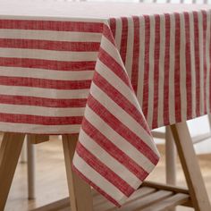 a red and white striped table cloth on top of a wooden table with two chairs in the background