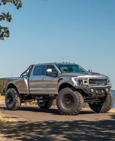 a silver truck parked on the side of a dirt road next to a body of water