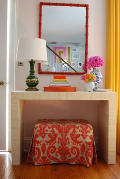 a table with a lamp, mirror and stool in front of it