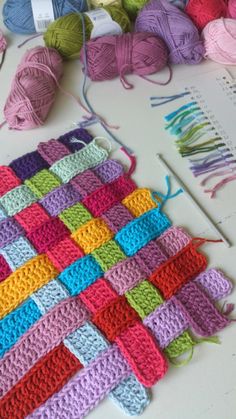 crocheted squares are arranged on a table with yarn